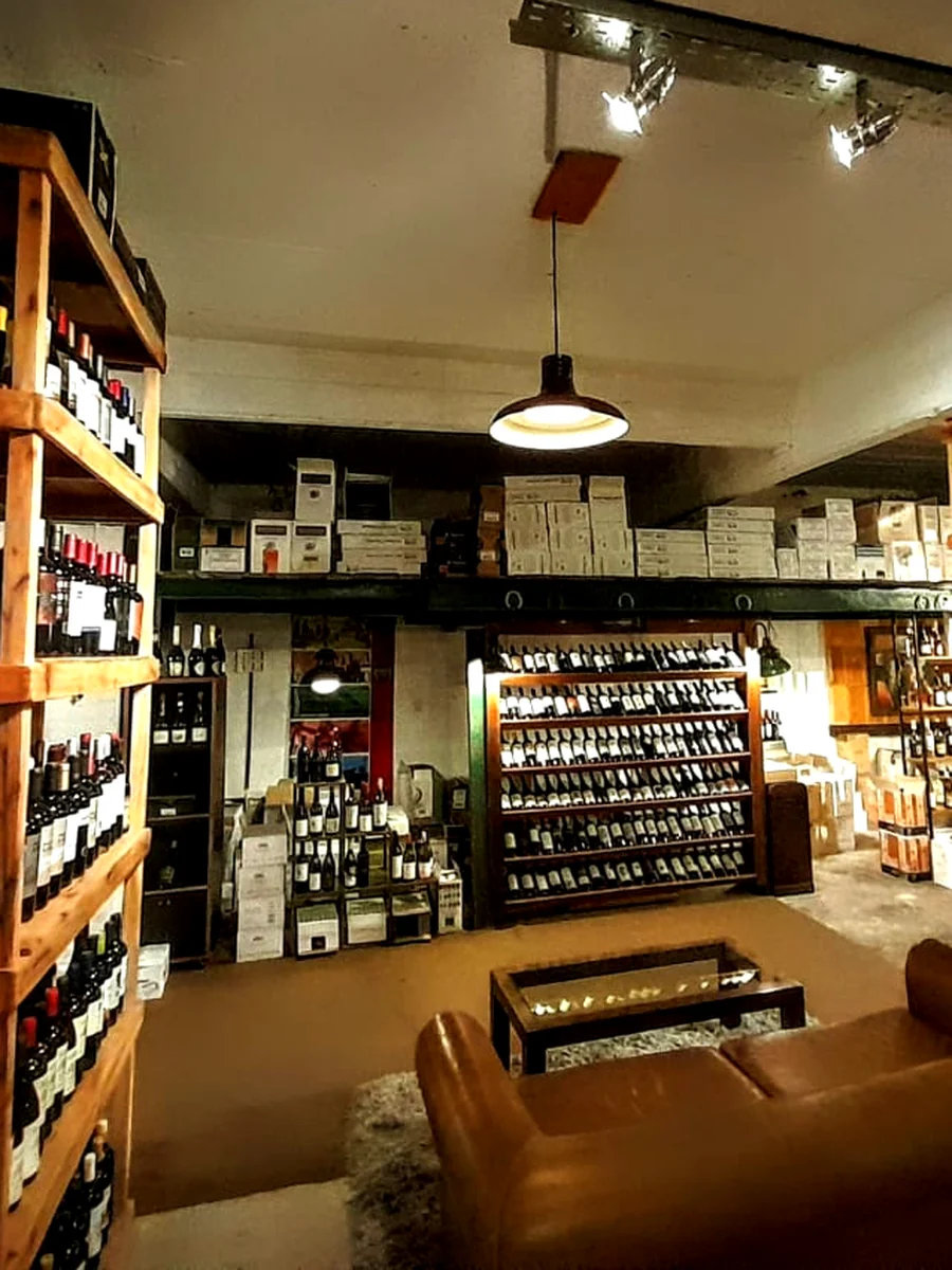 Interior de la cava de Club Segunda Copa en Martínez, con estanterías de vino y sillón para sentarse a charlar